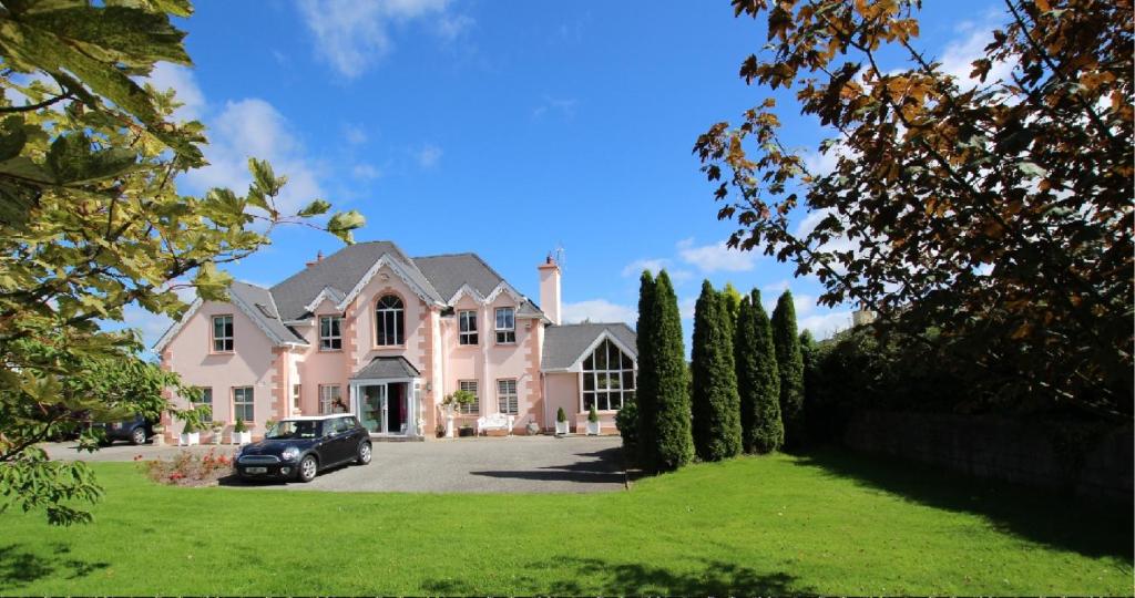 a large pink house with a car parked in the driveway at Maple Lodge in Wexford
