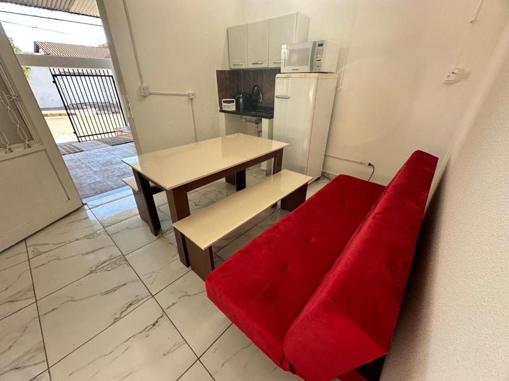 a red couch in a kitchen with a table and a refrigerator at Casa MR Brutomesso 2 in Londrina