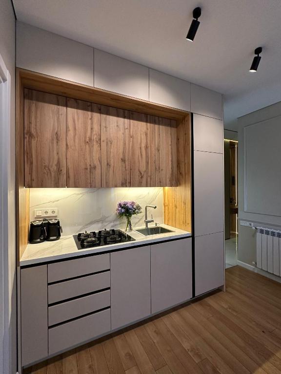 a kitchen with white cabinets and a stove top oven at Home Side Apartment in Batumi