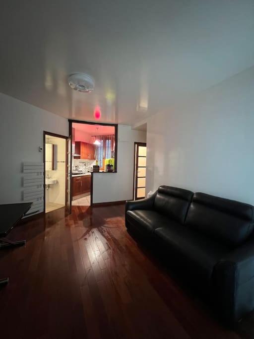 - un salon avec un canapé en cuir noir et du parquet dans l'établissement Appartement calme paris, à Paris