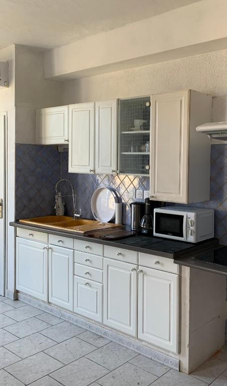 une cuisine avec des armoires blanches et un micro-ondes dans l'établissement Vigneronne, à Mèze