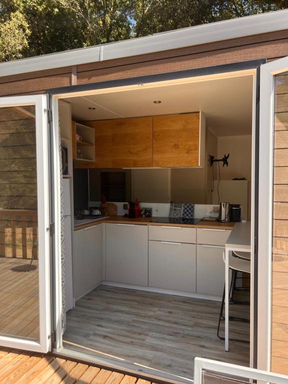 Il comprend une cuisine avec des placards blancs et une terrasse. dans l'établissement Mobilhome dans écrin de verdure, à Greffeil