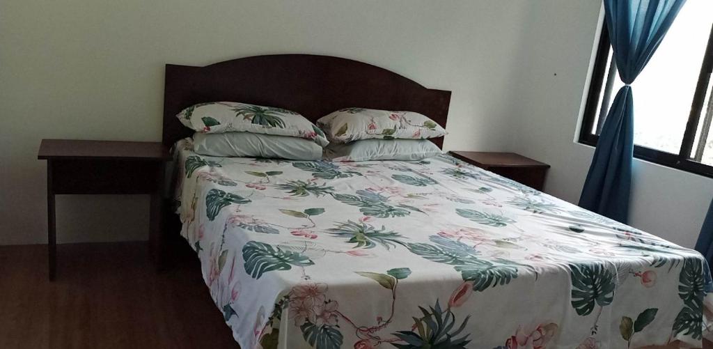 ein Bett mit einer geblümten Tagesdecke und zwei Kissen in der Unterkunft Soul Shine Beach House Cozy Studio with Wi-Fi in Bacungan