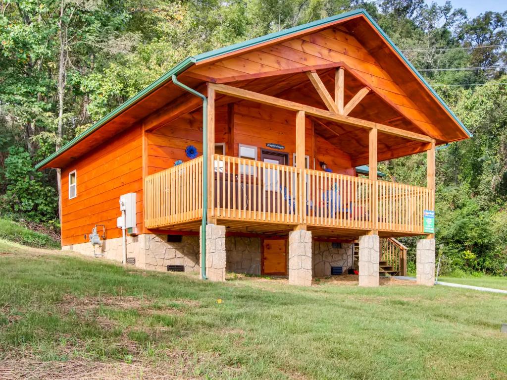 a large wooden cabin with a deck on a field at River Getaway #2326 in Pigeon Forge