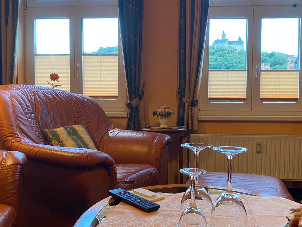 a living room with a leather chair and a table with wine glasses at Altstadt-Refugium - Schlossblick, Sauna, Parkplatz, Innenstadt, Wow Sky Sport BL in Wernigerode