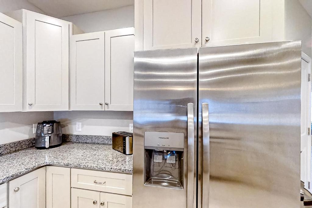 a stainless steel refrigerator in a kitchen with white cabinets at Old Bryan Salento - A in Myrtle Beach
