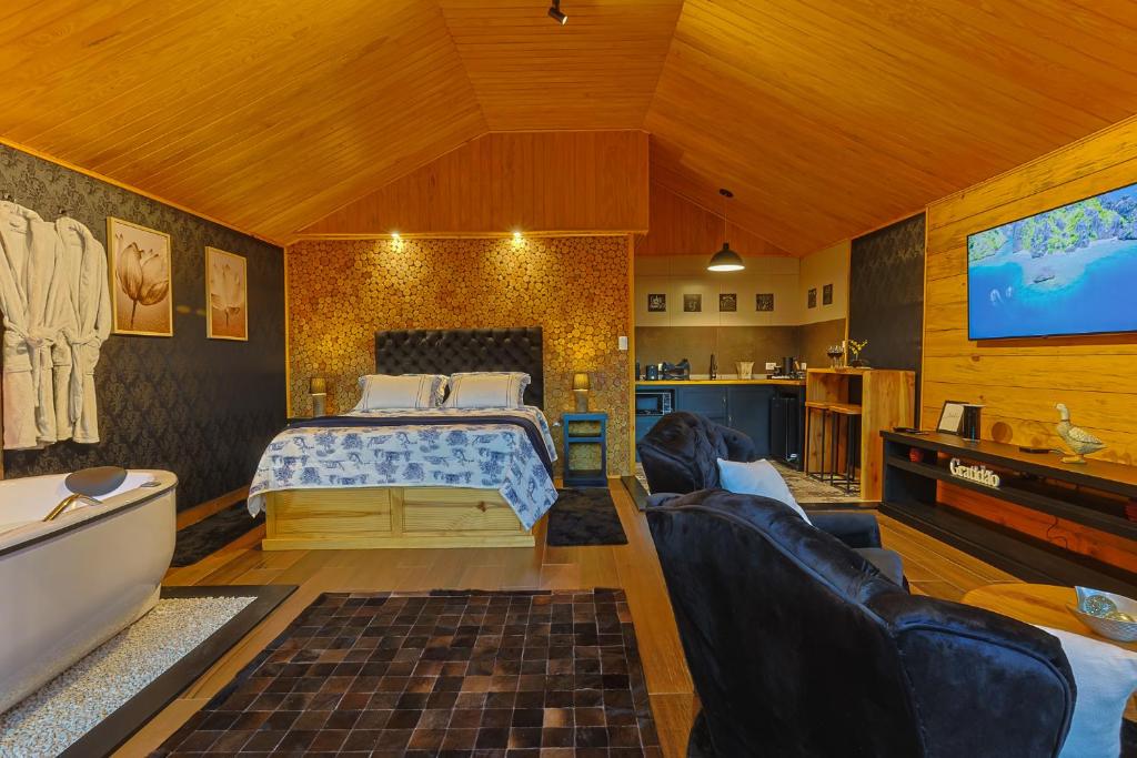 a bedroom with a bed and a tub and a tv at Requinte dos Pinhais Chalé in Santo Antônio do Pinhal