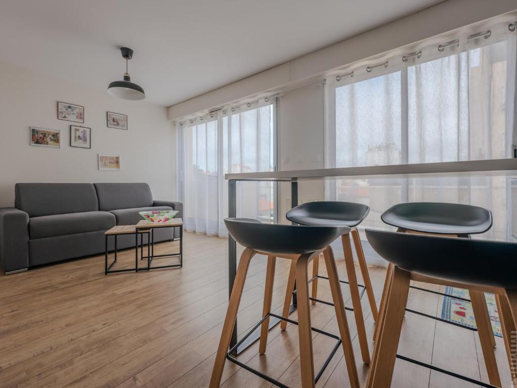- un salon avec un canapé et deux tabourets de bar dans l'établissement Appartement 1 chambre, balcon et accès direct à la plage - FR-1-197-596, à Les Sables-dʼOlonne