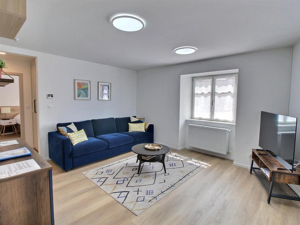 un salon avec un canapé bleu et une télévision dans l'établissement Gîte Alsacien pour 4 pers. rénové avec goût au cœur du vignoble, route des Vins, Gueberschwihr. - FR-1-722-9, à Gueberschwihr