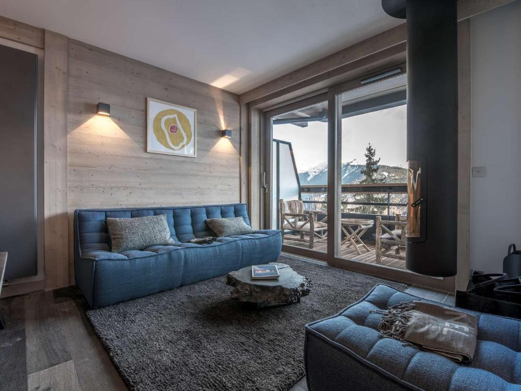 un soggiorno con un divano blu e una grande finestra di Appartement 51 m² - 4 pers - Courchevel Village - Centre station - Proche pistes - SPA - Parking - FR-1-631-201 a Courchevel