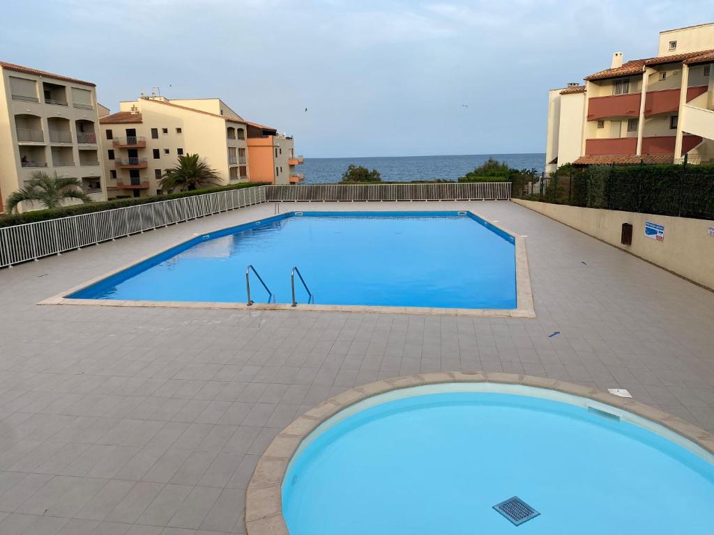 une grande piscine bleue au milieu d'un bâtiment dans l'établissement Studio cabine loggia et terrasse secteur prisé des falaises, au Cap d'Agde