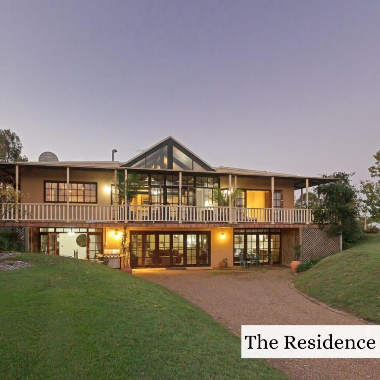 a large house with a balcony on top of a yard at Woolshed Hill Estate in Pokolbin