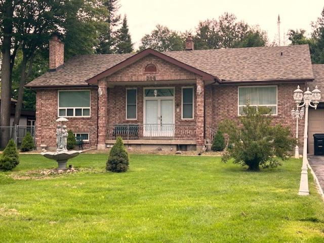 a brick house with a porch and a grass yard at Leslie in Wasaga Beach