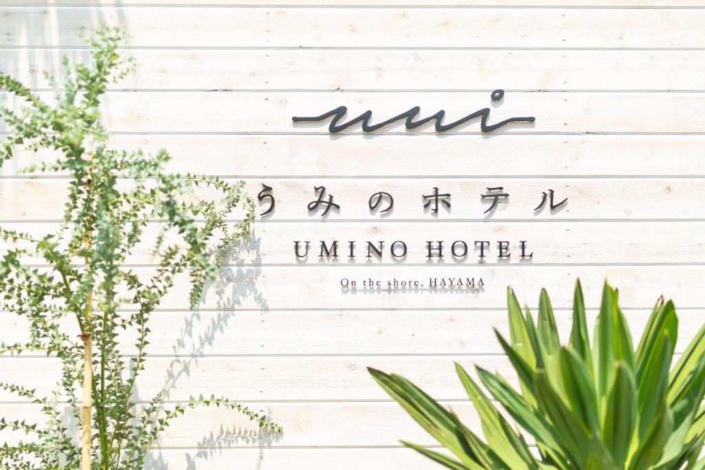 a sign on a white wall with plants at Hayama Umino Hotel in Hayama