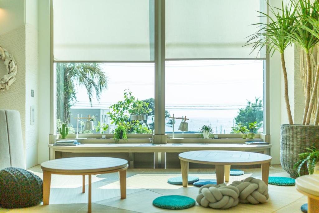 a living room with two tables and a window at Hayama Umino Hotel in Hayama