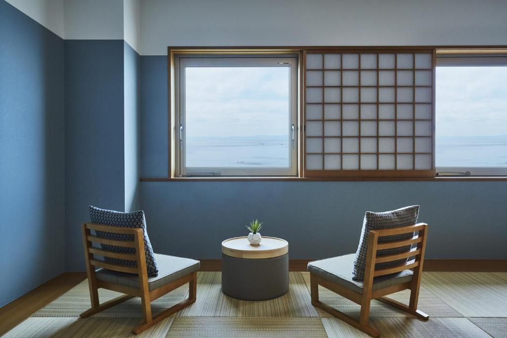 two chairs and a table in a room with two windows at Hayama Umino Hotel in Hayama
