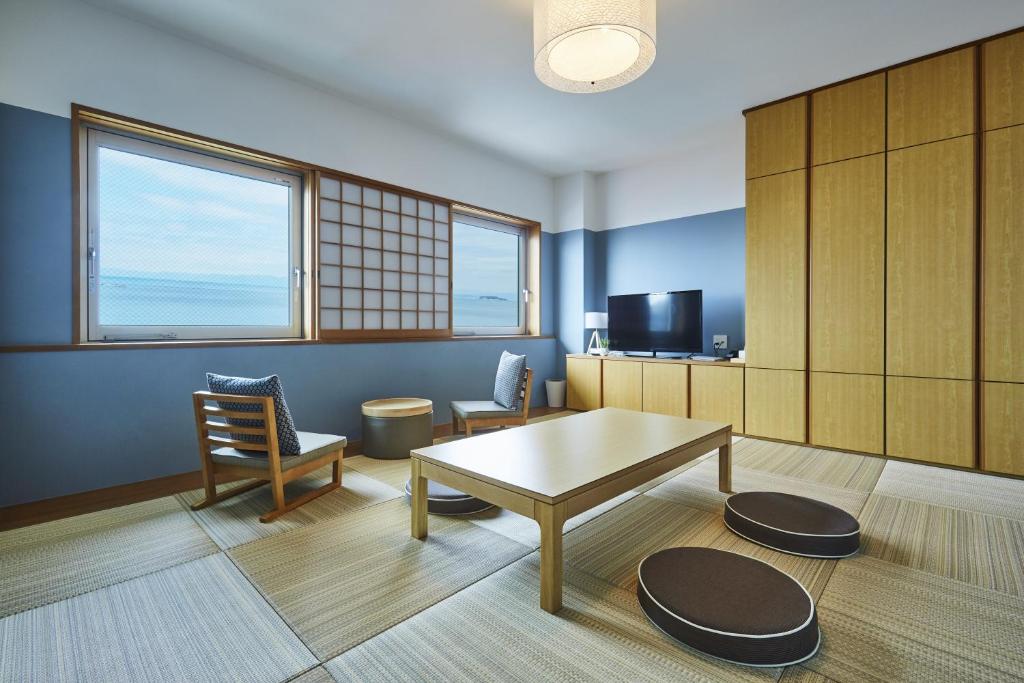 a room with a table and chairs and a tv at Hayama Umino Hotel in Hayama
