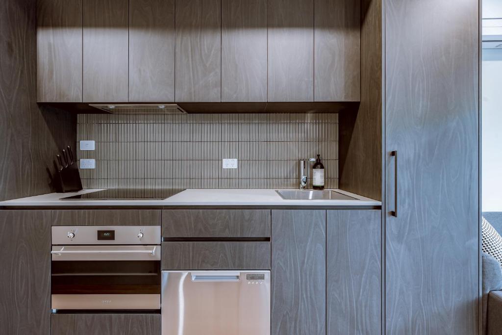 una cucina con mobili in legno e un frigorifero bianco di Modern apt in heart of the city a Canberra