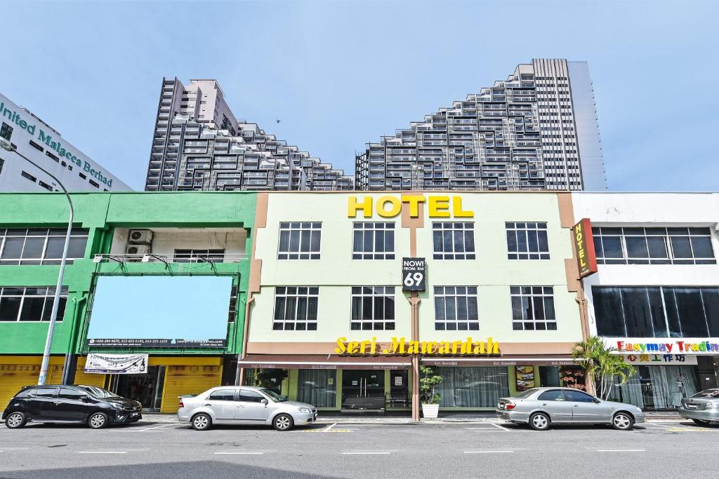 a hotel with cars parked in a parking lot at Seri Mawardah Hotel in Malacca