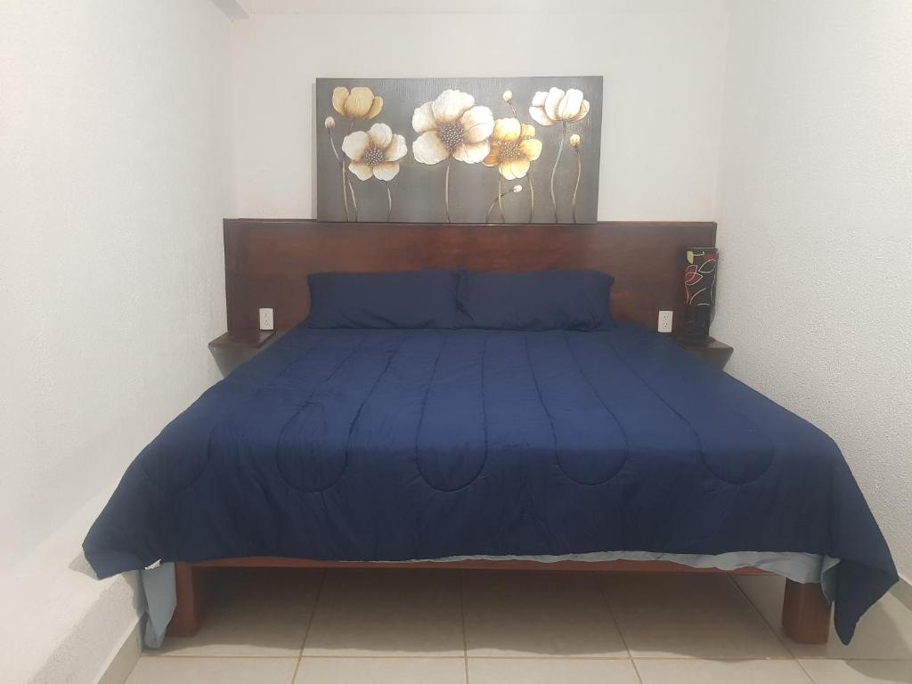 - un lit avec une couette bleue dans une chambre dans l'établissement Departamento los pinos 1, à Zurumútaro