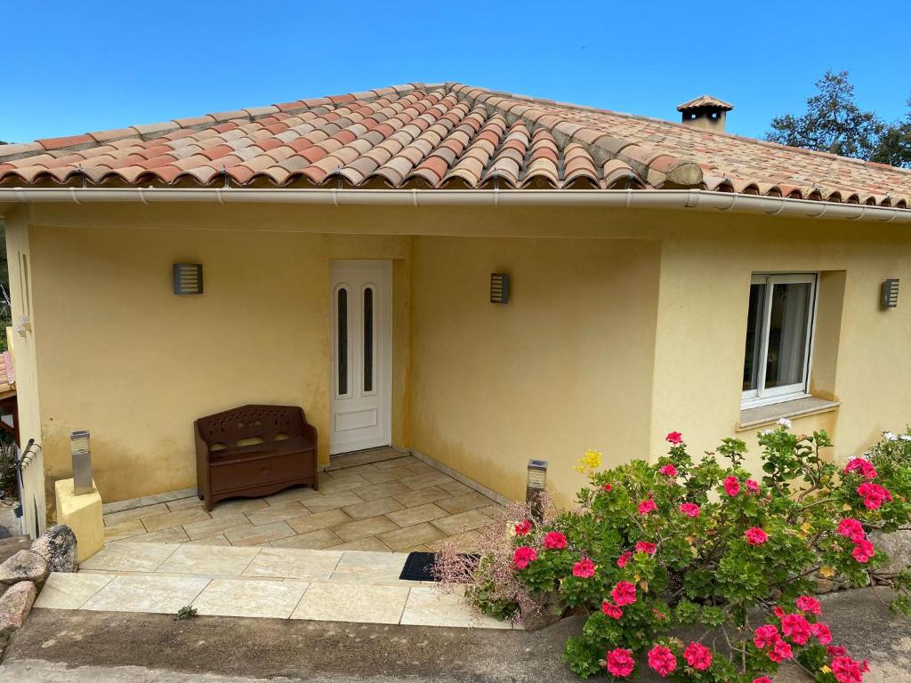 une petite maison jaune avec une porte et des fleurs roses dans l'établissement Les arbousiers de Murateddu, à Porto-Vecchio