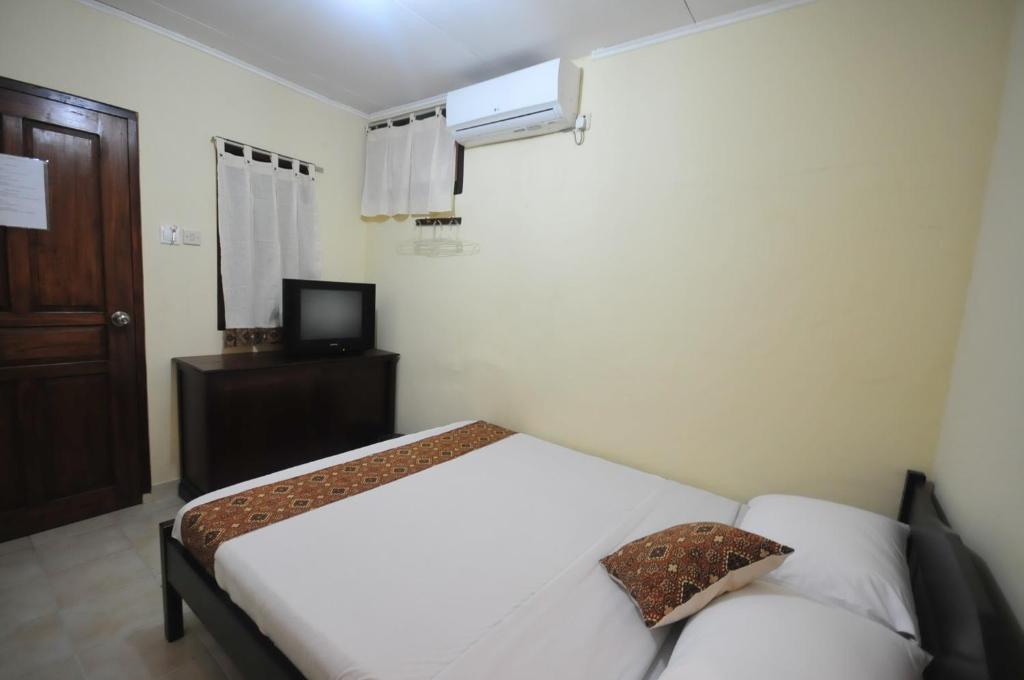 a bedroom with a white bed and a television at Andrea Hotel in Yogyakarta