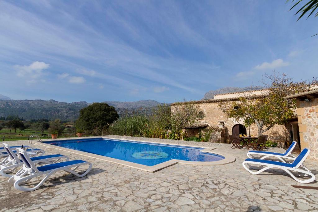 een zwembad met 2 ligstoelen en een huis bij Villa Plana Morro in Pollença