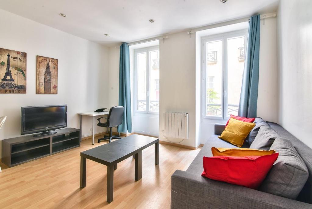 un salon avec un canapé et une télévision dans l'établissement GuestReady - Cosy Apartment in Le Marais, à Paris