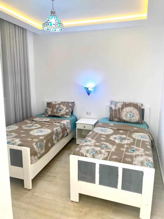 une chambre avec deux lits et un lustre dans l'établissement ResidenceHbiba-Appart2-RDC, à Ḩammām al Ghazzāz