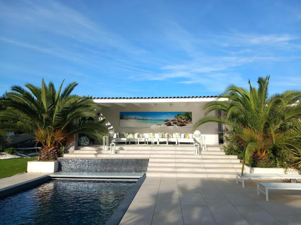 une villa avec piscine et palmiers dans l'établissement Villa Victoria, à Marennes