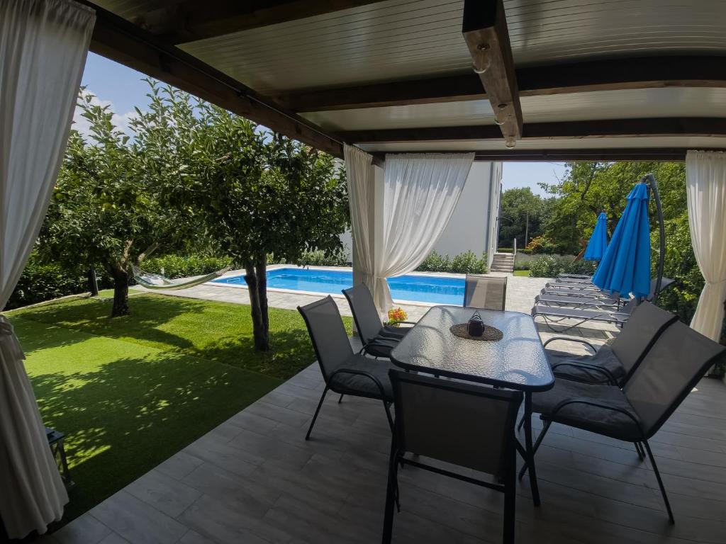 a patio with a table and chairs and a pool at Villa Hedera in Drniš