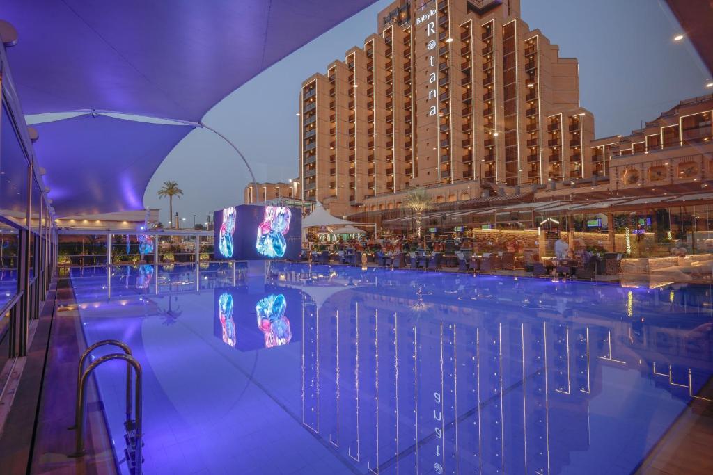 バグダッドにあるBabylon Rotana Hotelの大きな建物を背景に広いスイミングプール