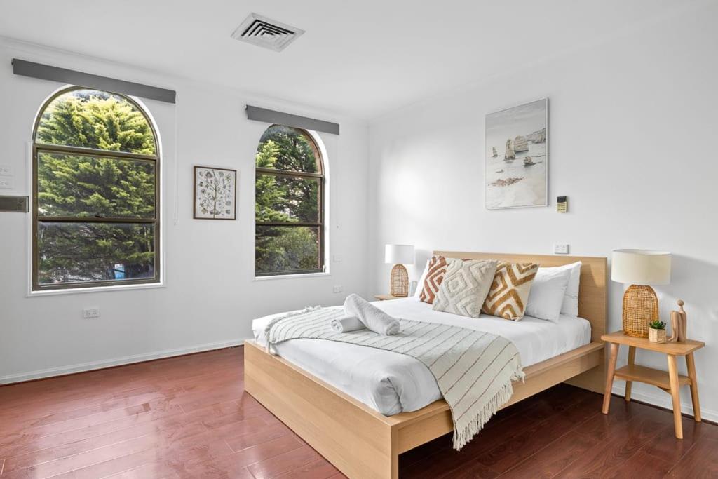 una camera da letto bianca con un letto e due finestre di Luxe Ensuite Queen Room - Close to Stations & Shops a Bankstown