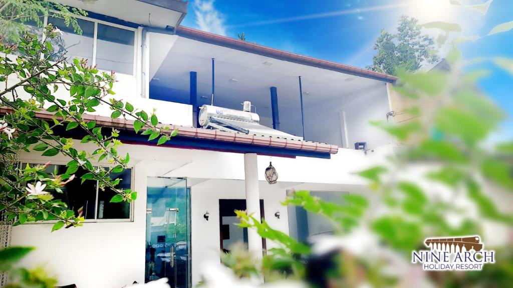 a train on the side of a white house at Ella, Nine Arch Holiday Resort in Ella