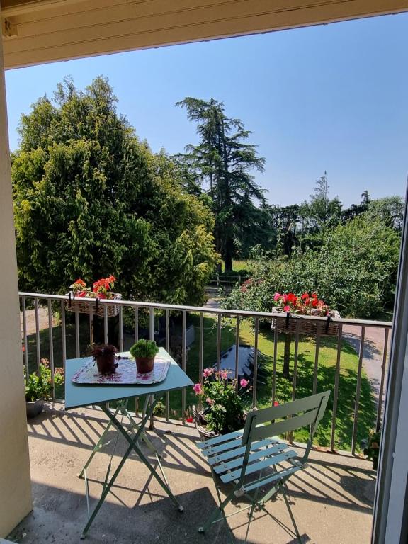 a table and chairs on a balcony with flowers at La Maison du Mont in Graignes