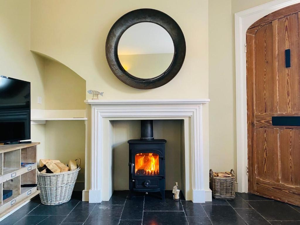 a fireplace in a living room with a mirror at Cosy 2 bed cottage in beautiful Orford in Orford