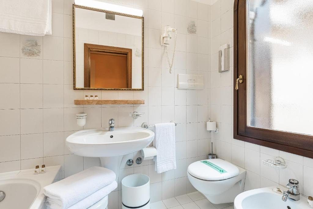 a white bathroom with a sink and a toilet at Hotel Marconi in Venice