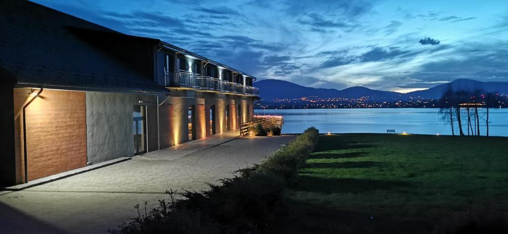 a building next to a body of water at night at Noclegi Laguna in Żywiec