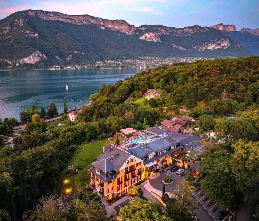 an aerial view of a hotel with a lake and mountains at Les Tr&eacute;soms Lake and Spa Resort in Annecy