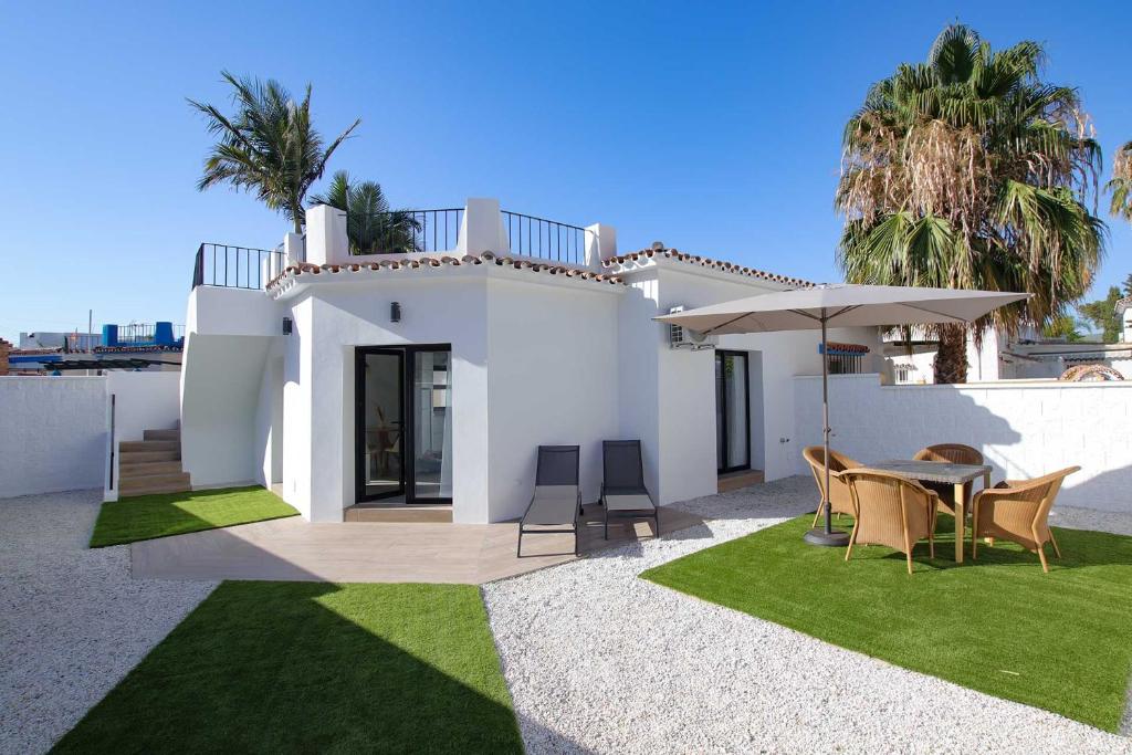 a white house with a table and an umbrella at Linda Vista Beach Apartment in Marbella