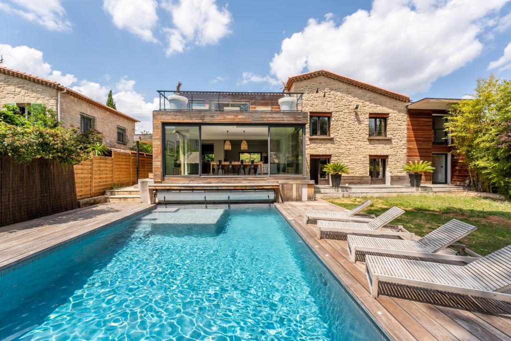 une piscine avec des chaises et une maison dans l'établissement Le plongeoir dans Montpellier, à Montpellier