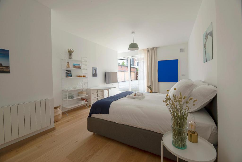 une chambre avec un lit et un vase de fleurs sur une table dans l'établissement Le Petit Vasselot, à Rennes