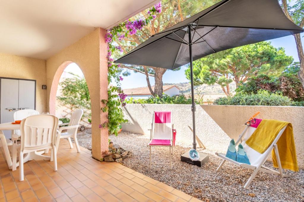 a patio with a table and chairs and an umbrella at Appartement aux Aloès in Cerbère