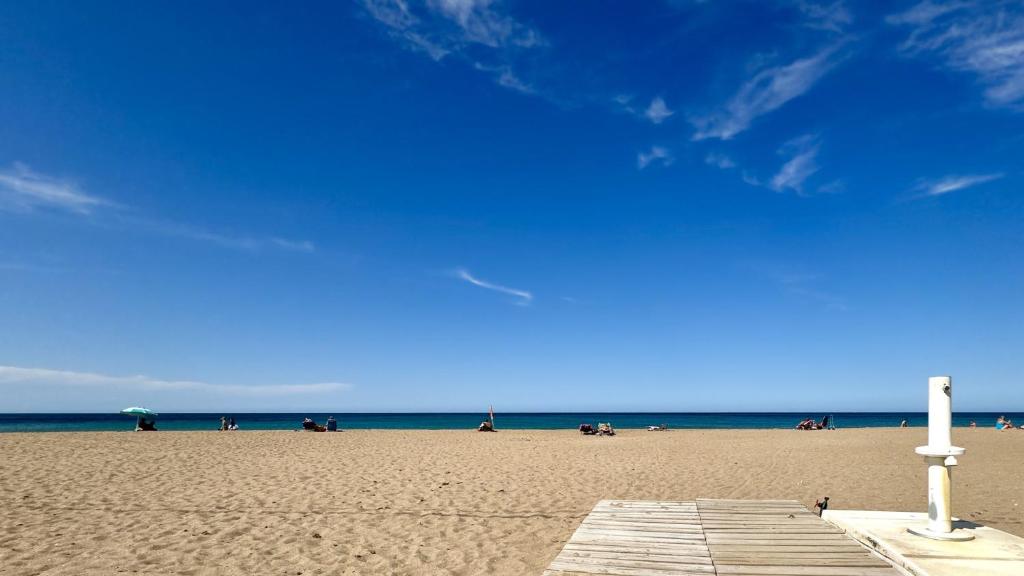 a beach with people sitting on the sand and the ocean at Las perlas VYBDenia in Denia