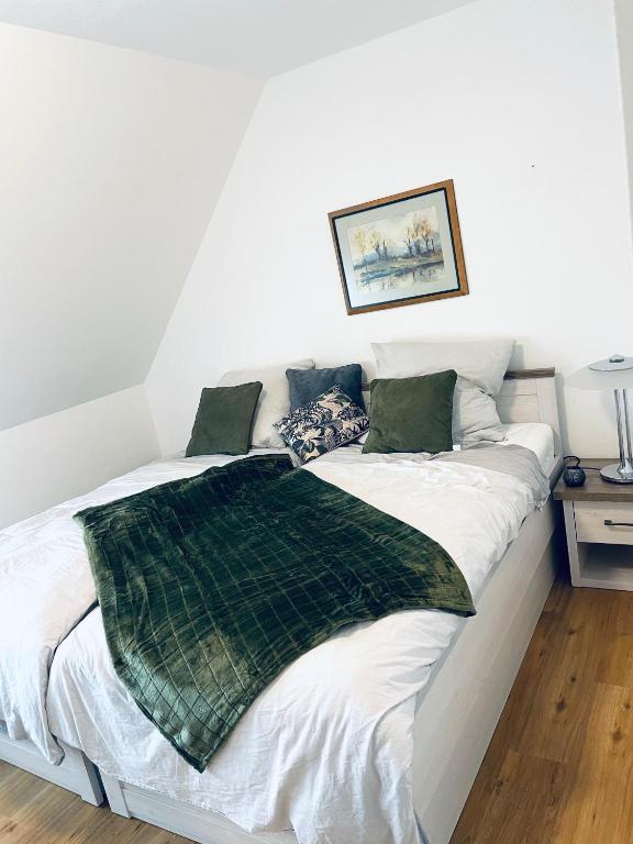 a bed with a green blanket on top of it at Apartment Charly in Steinbeck in Recke