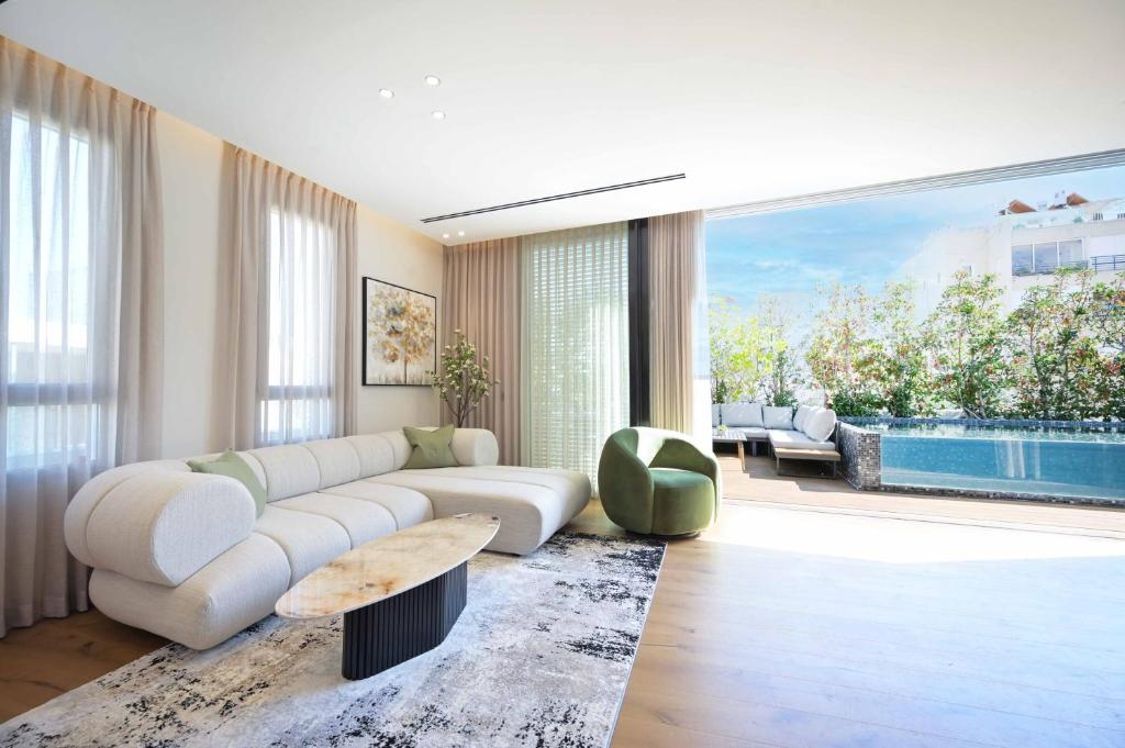 a living room with a white couch and a pool at Luxury Modern 3BR Penthouse w Pool by HolyGuest in Tel Aviv