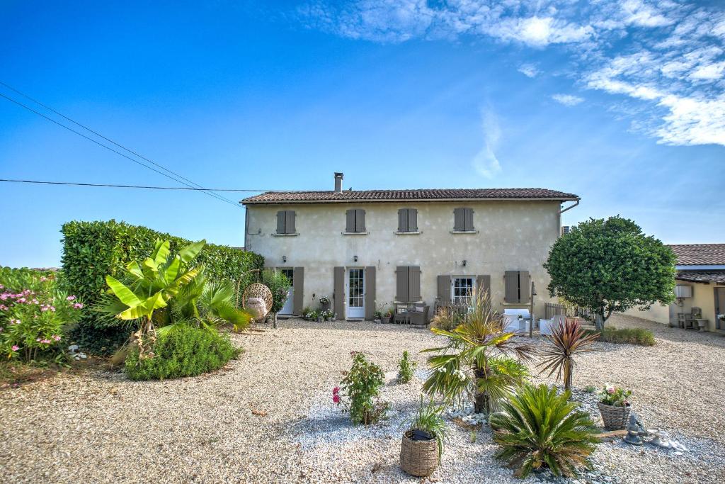 une grande maison blanche avec des plantes devant elle dans l'établissement Le Nid Du Charmant, à Montagne