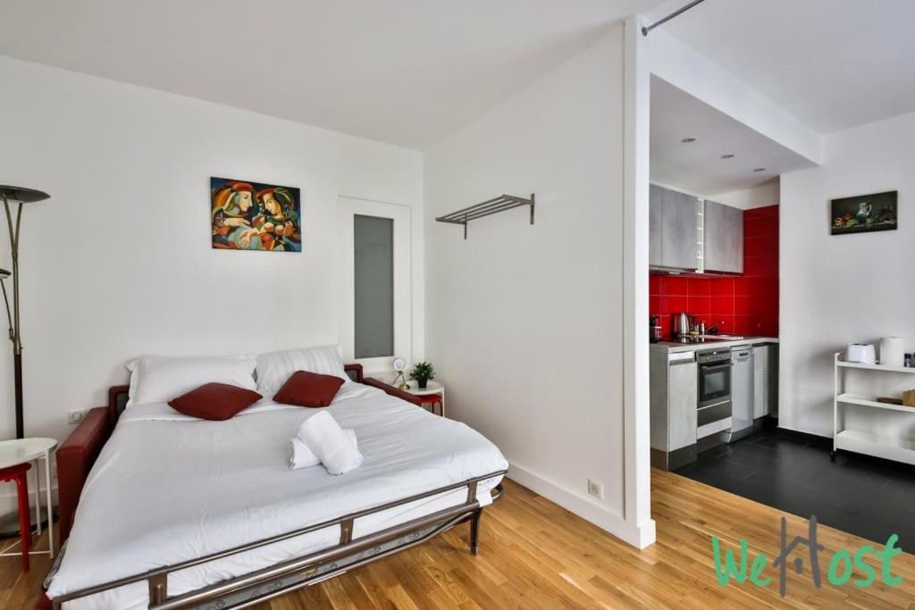 Cet appartement comprend une chambre avec un lit blanc et une cuisine. dans l'établissement Charming Studio -2 persons - Paris 10, à Paris