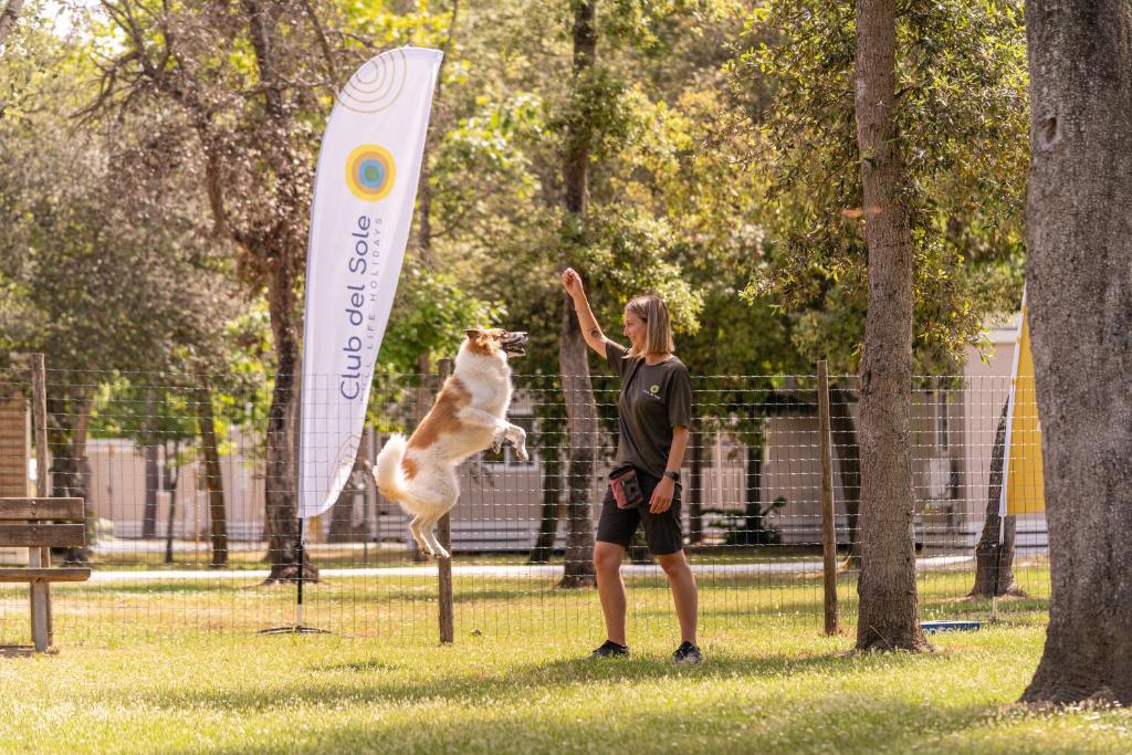 a woman playing with a dog in a park at Club del Sole Viareggio Family Collection in Torre del Lago Puccini