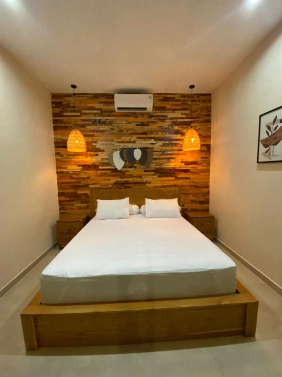 a bedroom with a bed with a wooden wall at LM Home Mendira in Candidasa